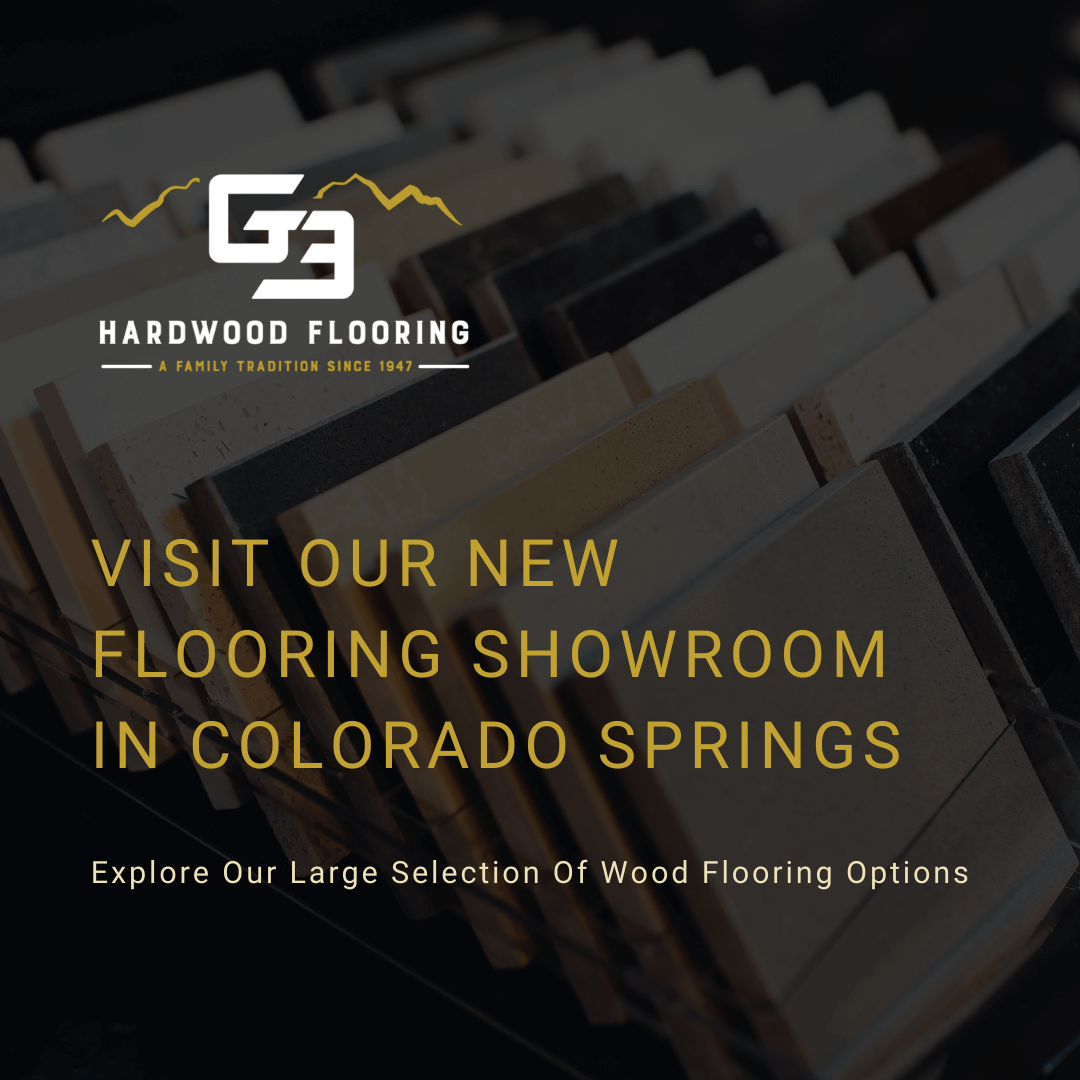 The background of the graphic is an image of a bunch of different wood flooring samples. There's a dark overlay over the image and the title of the blog in the center, which reads, "Visit Our New Flooring Showroom In Colorado Springs".